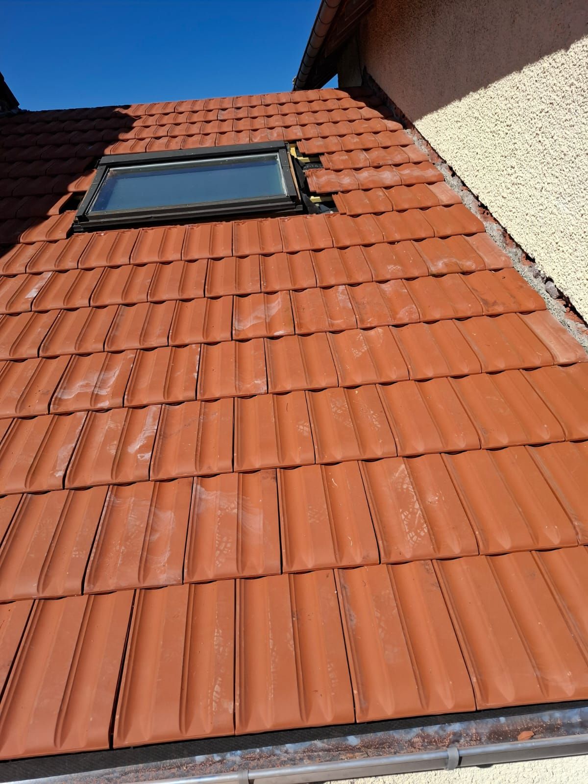 Fenêtre de toit neuve sur une toiture en tuiles