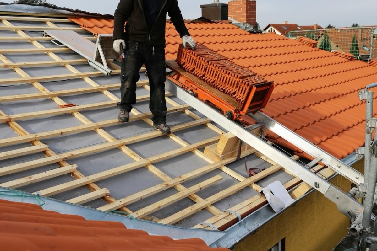 Pose de tuiles sur écran et liteaux, sur un chantier de couverture